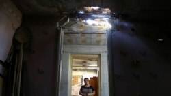 ARMENIA -- A woman stays inside a house, which locals said was damaged during a recent shelling by Azerbaijani forces, in armed clashes on the border between Azerbaijan and Armenia, in the village of Aygepar, Tavush Province, July 15, 2020