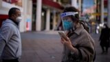 Egy védőmaszkot és arcvédőt viselő nő egy sanghaji bevásárlónegyedben 2023. január 3-án