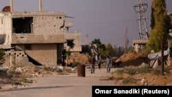 Дамаскіде қираған ғимараттың жанында кетіп бара жатқан адамдар. Сирия, 23 шілде 2017 жыл (Көрнекі сурет).