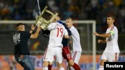 Pamje kur një simpatizues i Serbisë (i veshur me të zeza) e godet me karrige lojtarin Bala të Shqipërisë