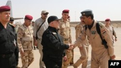 Премьер-министр Ирака Хайдер аль-Абади (в центре) здоровается с офицерами по прибытии в город Мосул. 9 июля 2017 года.