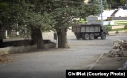 A military truck used by ethnic Armenian forces passes by a park in the center of Hadrut just days before local residents Benik Hakobian and Yuri Adamian were executed there.