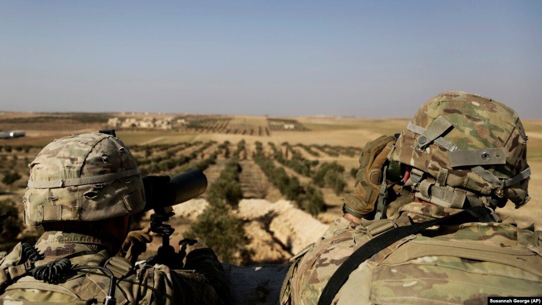 U.S. troops look toward the border with Turkey from a small outpost near the town of Manbij in northern Syria on February 7.