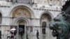 Italy -- People walk on a platform to cross Piazza San Marco (St Mark's square) flooded, Venice, 10Feb2009