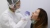 RUSSIA -- A health worker wearing protective gear takes a swab from a woman to test for the coronavirus disease (COVID-19) at Gemotest laboratory in Moscow, April 6, 2020