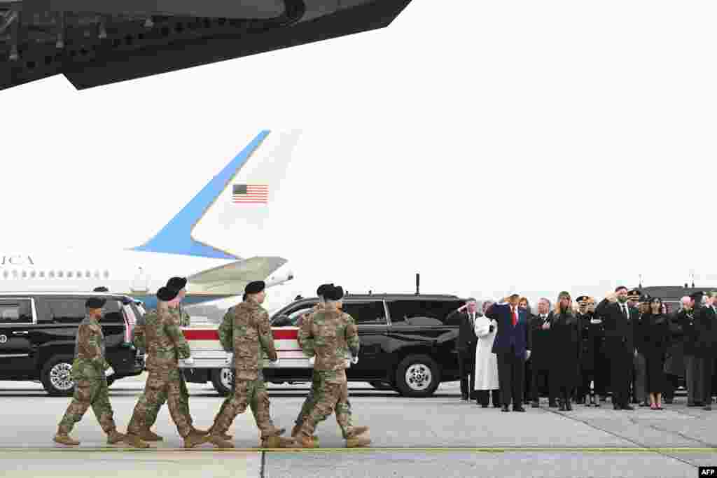 Президент США Дональд Трамп отдает честь, когда члены команды армии США несут покрытый флагом ящик с останками американского солдата сержанта 1-го класса Николь М. Амор, авиабаза Довер, штат Делавэр 