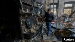 Donetsk sebitiniň ýaşaýjysy Pawel ýakynda bolan artilleriýa atyşygynda öldürilen goňşusynyň öýünde onuň goşlaryny ýygnaýar. 10-njy dekabr, 2022 ý.