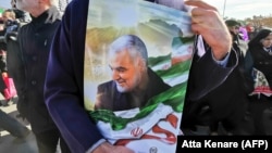 IRAN -- An Iranian man carries a portrait of slain Iranian General Qasem Soleimani, on the 40th day of his killing in a U.S. drone strike, during commemorations marking 41 years since the Islamic Revolution, in Tehran, February 11, 2020