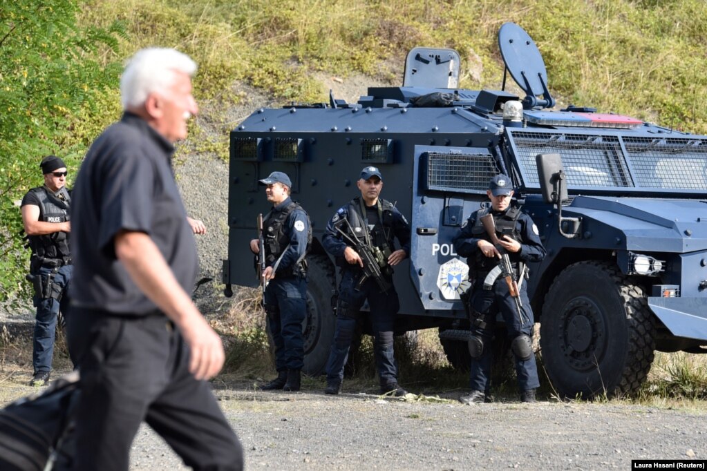 Një person duke ecur pranë pjesëtarëve të Policisë së Kosovës që po bënin rojë, në Jarinjë. (27 shtator)
