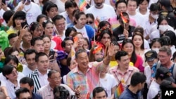 Premierul thailandez Srettha Thavisin, în centru, jos, salută participanții la marșul Pride de la Bangkok, la 1 iunie 2024.