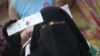 A veiled woman holds up her mobile phone. In Pakistan's conservative former tribal areas and beyond, women have become easy targets of schemes to illegally clone mobile SIM cards. (file photo)