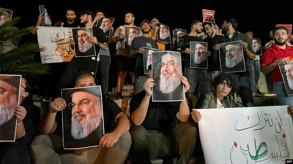 Demonstrators hold pictures of Hassan Nasrallah, late leader of the Lebanese group Hezbollah, during a protest vigil in the southern Lebanese city of Sidon on September 28.