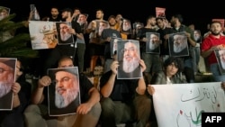 Demonstrators hold pictures of Hassan Nasrallah, late leader of the Lebanese group Hezbollah, during a protest vigil in the southern Lebanese city of Sidon on September 28.