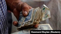 A farmer holds a wad of Cuban money