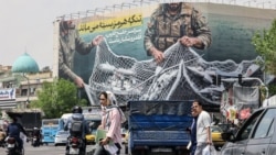 Iranian walks past a giant billboard reading "The Strait of Hormuz remains closed" on Revolution Square in Tehran on April 22.