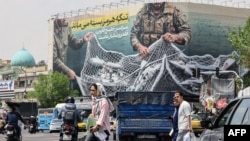 Іранці проходять повз велетенський білборд з написом «Ормузька протока залишається закритою» на площі Революції в Тегерані 22 квітня 2026 року