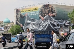 People on Revolution Square in Tehran on April 22 walk past a giant billboard saying "the Strait of Hormuz remains closed."