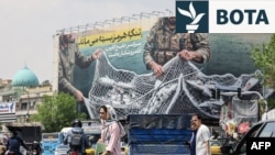 Iranianët duke kaluar pranë një bilbordi ku shkruan: "Ngushtica e Hormuzit mbetet e mbyllur". Teheran, 22 prill 2026.