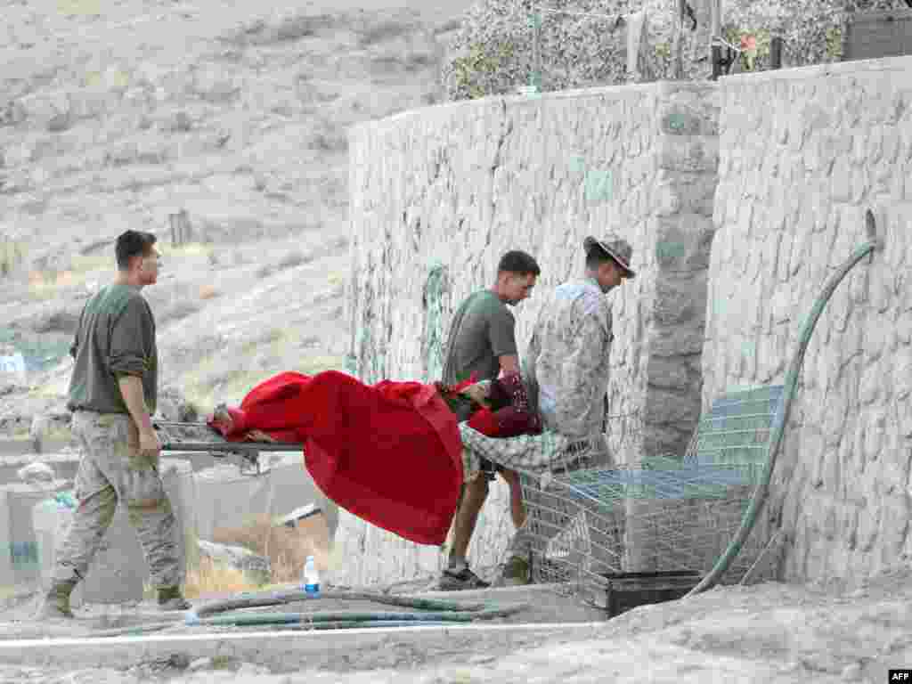 U.S. Marines carry a 13-year-old Afghan boy into a base in Kajaki, Afghanistan, to receive medical aid after he was severely wounded in blast. Photo by Scott Olson for AFP