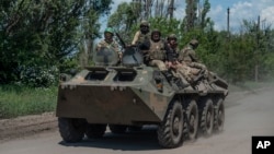 Ukrainian soldiers ride an armored vehicle on the front line near Bakhmut in the Donbas. 