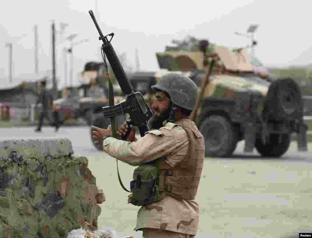 An Afghan National Army soldier takes up a position at the site of the suicide car bomb attack.