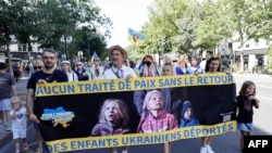 Demonstranti drže transparent na kojem piše: "Nema mirovnog sporazuma bez povratka deportovane ukrajinske djece" tokom skupa podrške Ukrajini u Parizu, 24. augusta 2025.