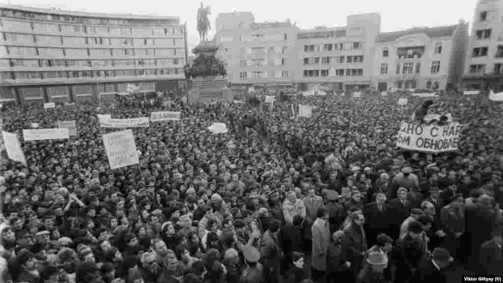 Това е друг митинг. Той се провежда ден по-рано, на 17.11.1989 г., и по тази причина би трябвало да се нарича &quot;първи&quot;. Но в 30-те изтекли години той така и не се сдобива с този етикет.&nbsp;Организиран е от БКП веднага след като опозицията е съобщила, че ще се събира пред Св. &quot;Александър Невски&quot;. Тогава това не се разглежда като &quot;издърпване на чергата&quot;. Хората за първи път са участници в една съвсем нова публичност. Някои отиват и на двата митинга, и това изглежда съвсем естествено.