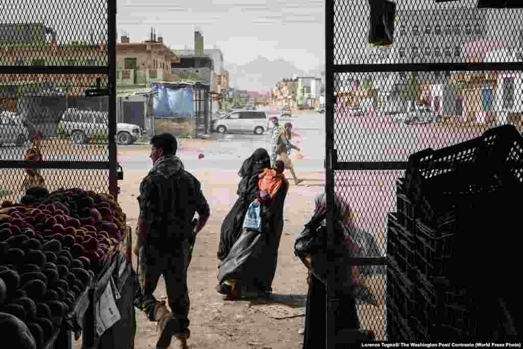 A woman begs outside of a grocery store in the village of Azzan, Yemen, on May 22, 2018. The village of Azzan was under the control of Al-Qaeda militants until the Shabwani elite forces liberated the area in December 2017. General News: First Prize, Stories - Lorenzo Tugnoli, Contrasto, for The Washington Post