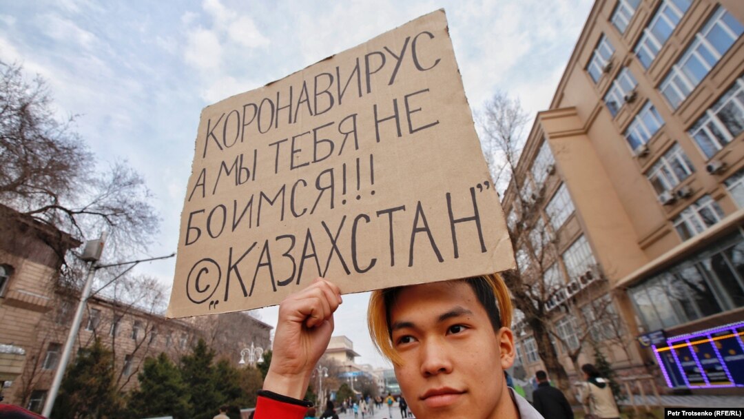 «Коронавирус, биз сендан қўрқмаймиз» деб ёзилган плакатни тутган йигит, 14 март, 2020, Олмаота.