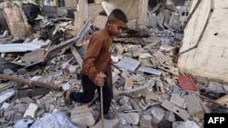 Момче се разхожда сред развалините на сграда след нощна израелска бомбардировка в Рафах в южната част на Ивицата Газа на 25 март 2024 г.