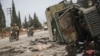 Syrian opposition fighters drive past a damaged government vehicle south of Hama on December 7. 