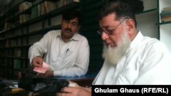 Haji Rasheed (right) bags a book for a customer in front of the dwindling stock of books at his Maktaba-e Sarhad bookstore in Peshawar.