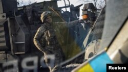 Украински војник стои во близина на воено возило во градот Бахмут во првата линија на фронтот во регионот Донецк, Украина, 19 февруари 2023 година.