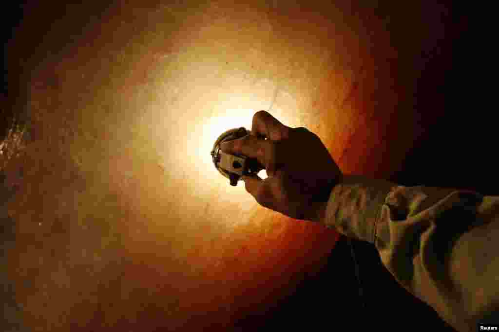 A guide shines his light onto transparent rock salt for visitors to Khewra.