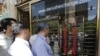 Iranians check exchange rates outside a bank in Tehran. The country's currency, the rial, has lost 70 percent of its value in recent years, causing much economic hardship. (file photo)