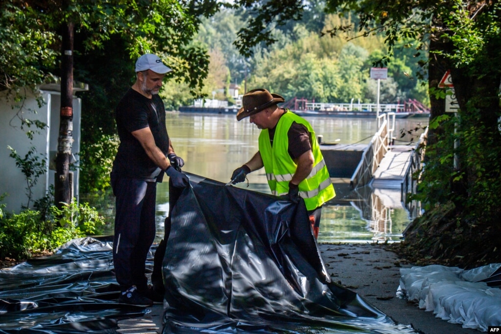 „Ungaria a învățat protecția împotriva inundațiilor în timpul inundațiilor anterioare, iar profesioniștii și voluntarii știu exact ce au de făcut”, a declarat Orban. Szentendre, la 20 km nord de capitala Budapesta, la 18 septembrie 2024: Locuitorii lucrează pentru a proteja malurile Dunării cu prelate și cu o barieră din saci de nisip.