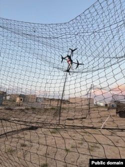An image released by the Israeli military showing an FPV drone suspended in netting over Israeli military vehicles at an unknown location.