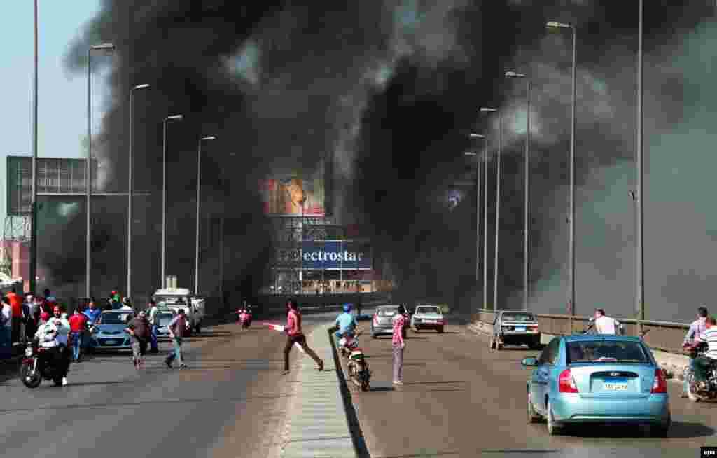 Egyptians flee the scene as others arrive on a bridge while smoke rises following clashes bertween opponents and supporters of ousted President Muhammad Morsi in Cairo. (epa/Ahmed Khaled)