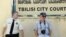 Полицейский смотрит на фотографа у здания городского суда Тбилиси, который в тот момент приговорил четырех журналистов к четырем годам тюрьмы по обвинению в шпионаже в пользу России. 22 июля 2011 года.