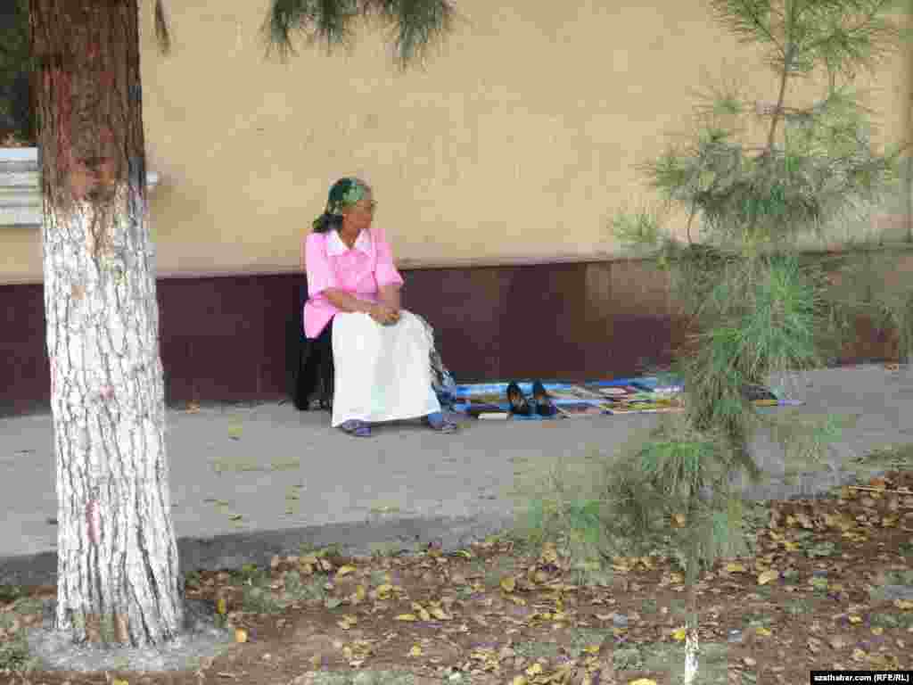 Köçäniň gyrasynda kitaplary satyp oturan gartaşan bir zenan