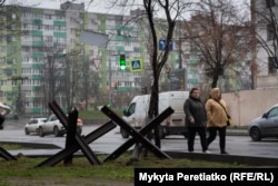 Women pass by anti-tank hedgehogs near high-rise residential buildings in Dnipro on December 12.