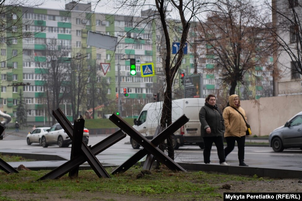 Women pass by anti-tank hedgehogs near high-rise residential buildings in Dnipro on December 12.