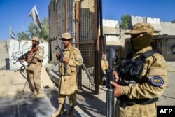 Armed Taliban security personnel keep guard near the closed gate of the border crossing between Afghanistan and Pakistan at Spin Boldak on October 12, 2025.