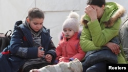 A woman sits with children as evacuees, including civilians who left the area near the Azovstal steel plant in Mariupol, arrive at a temporary accommodation center in the village of Bezimenne in the Donetsk region on May 1.