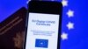 A picture taken on June 16, 2021 in Brussels shows a passeport behind a mobile phone whose screen bears a EU Digital Covid certificate. 