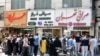 Iranians, wearing protective masks without observing social distancing, queue outside a money exchange office in the capital Tehran on May 9, 2020