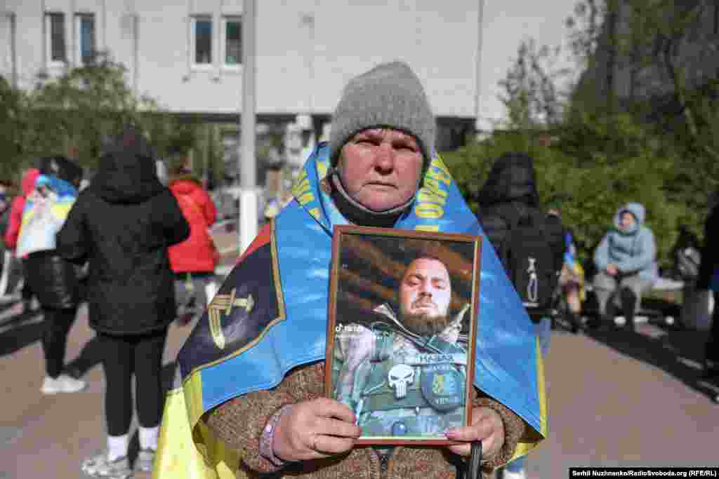 Людмила тримає портрет сина Юрія. Йому 38. На її спині український прапор з емблемою бригади, де він служив.«Він працював будівельником, пішов добровольцем у 2023 році, отримав поранення, повернувся. Я з ним останній раз розмовляла 15 грудня 2024 року, а сповіщення (сповіщення про зникнення військовослужбовця безвісти – ред.) надійшло 18 грудня, зник біля Новотроїцького…» – розповіла мама військового.«У нього донька є, 16 років, сирота, мама померла, батька немає, я опікунка. Хочу дізнатись хоч щось про нього», – зі сльозами говорить Людмила