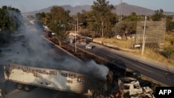 Un camion despre care se crede că a fost incendiat de grupuri criminale organizate ca răspuns la operațiunea armatei mexicane împotriva liderilor cartelului de droguri. Statul Jalisco, Mexic. 22 februarie 2026.