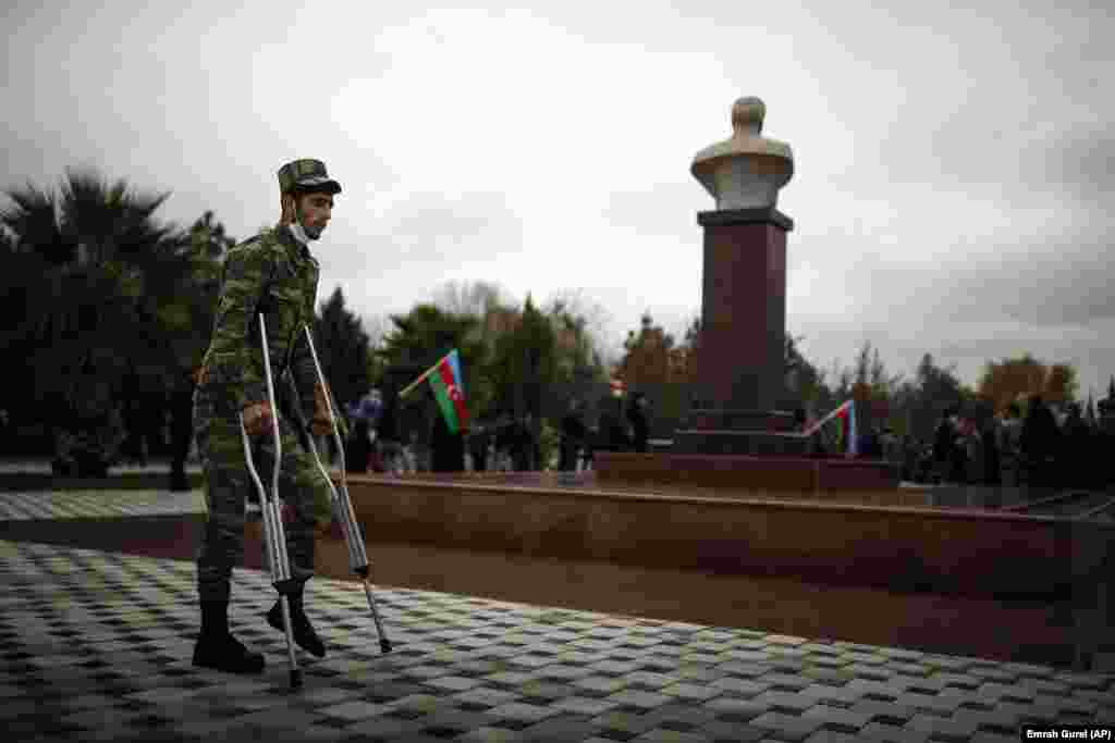 Një ushtar i plagosur kalon pranë bustit të babait të presidentit të Azerbajxhanit Ilham Aliyev, i cili ka qenë po ashtu president. Busti është i ngritur në Aghjabadi të Azerbajxhanit.(AP/Emrah Gurel)