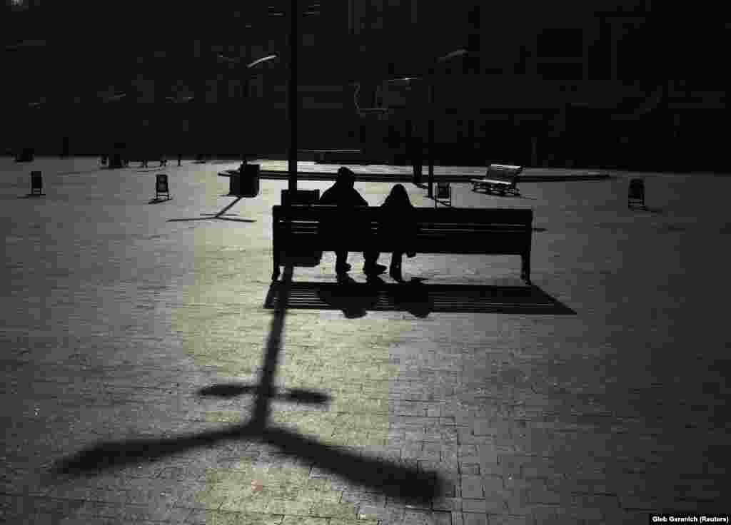 People rest on a bench on a cold, sunny autumn day in central Kyiv, Ukraine. (Reuters/Gleb Garanich)